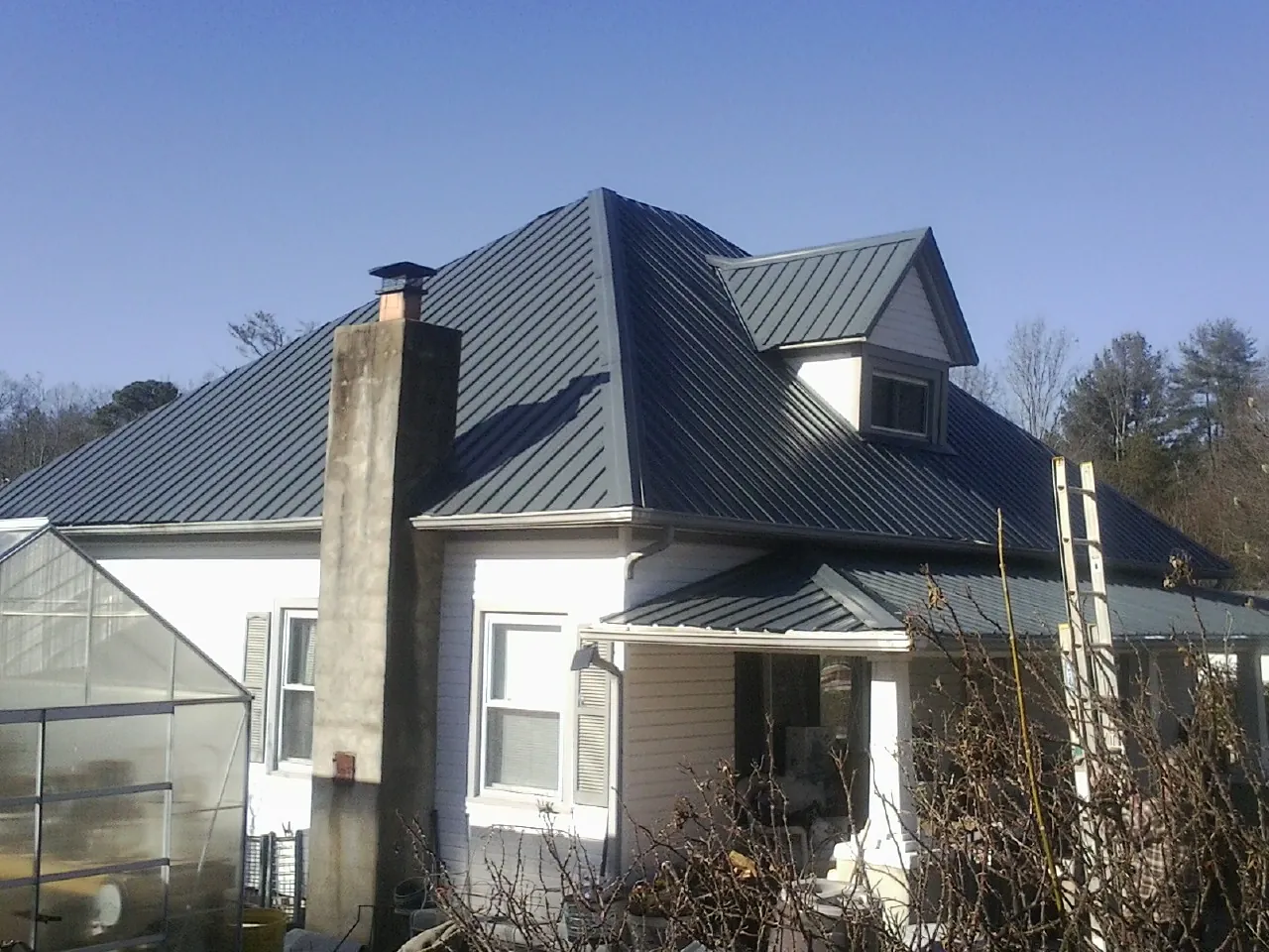 Dark blue standing seam metal roof on a white farmhouse with dormer — Slate & Tile Roof Repair by Roofing Brothers in Barnesville