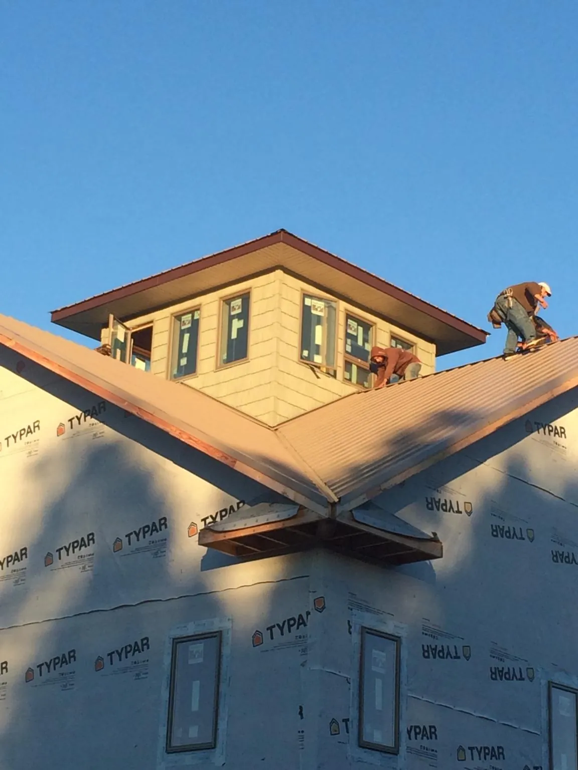 Roofers working around a rooftop cupola on a new metal roof at sunset — Roof Waterproofing in Barnesville by Roofing Brothers